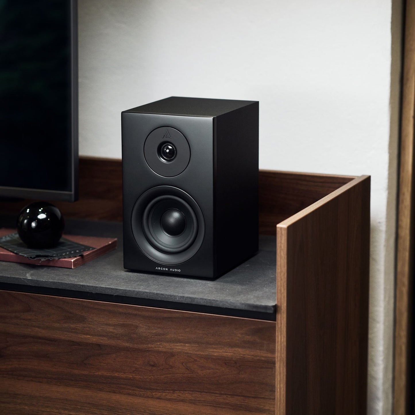 Argon Audio Forus 4 Regallautsprecher schwarz Lifestyle auf Sideboard neben Fernseher