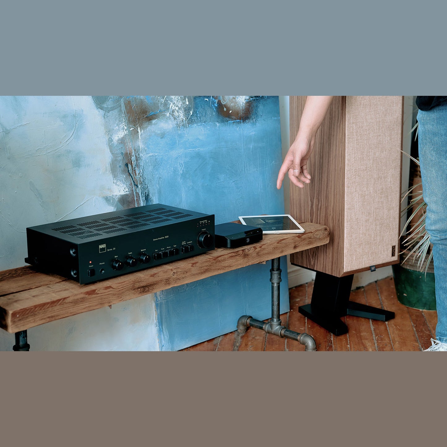 Bluesound Node Nano Netzwerk-Streamer Lifestyle auf Wandbrett mit Verstärker und Regallautsprecher