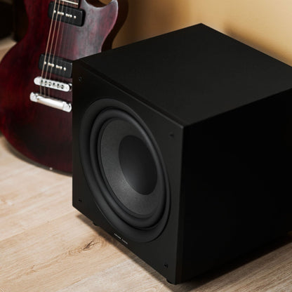 Argon Audio Malmö Sub 10 Aktiv-Subwoofer schwarz Lifestyle im Wohnraum neben E-Gitarre