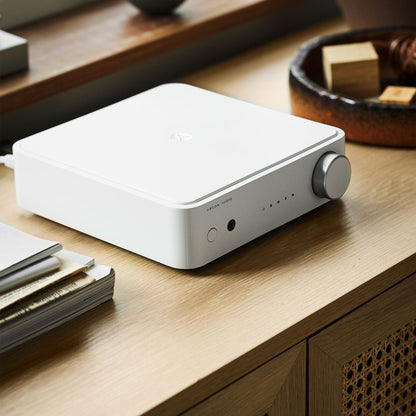 Argon Audio SA2 Streaming-Verstärker weiss Lifestyle auf dem Sideboard neben Zeitschriften