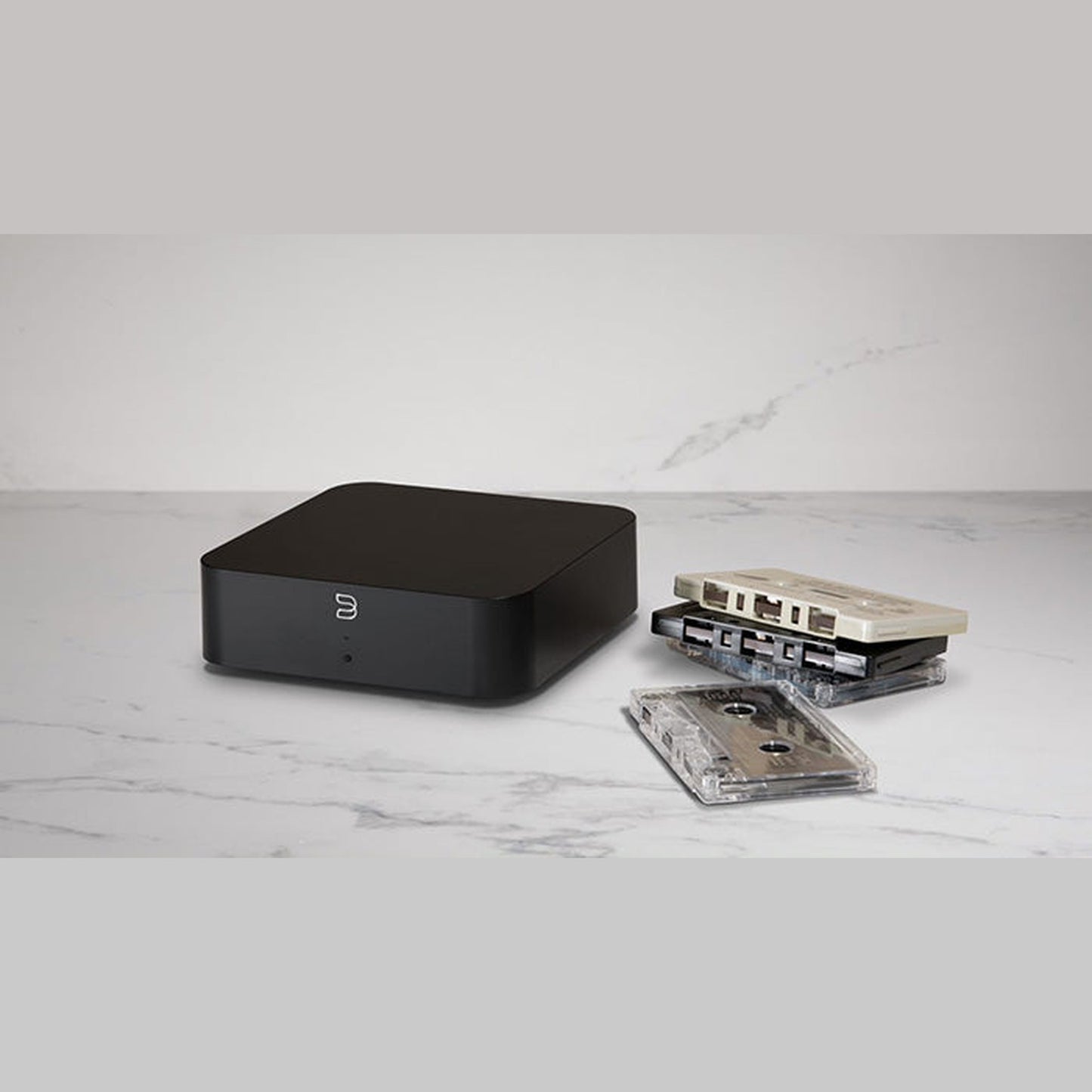 Bluesound Hub Multiroom-Streaming-Hub Lifestyle auf Marmorablage neben Musikkassetten