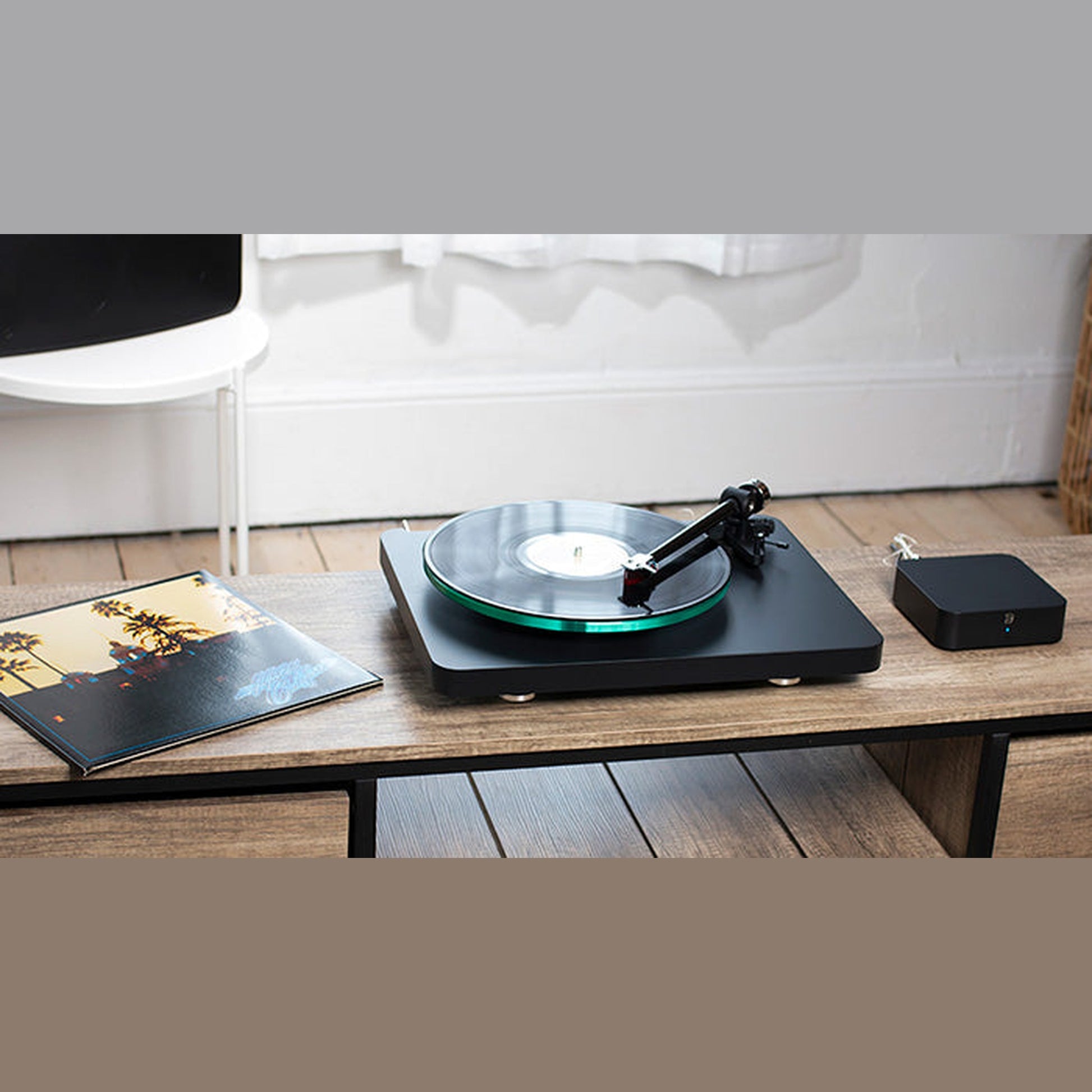 Bluesound Hub Multiroom-Streaming-Hub Lifestyle auf Beistelltisch neben Plattenspieler