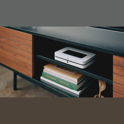 Bluesound Node Netzwerk-Streamer Weiss Lifestyle im TV-Möbel aus Holz über Büchern
