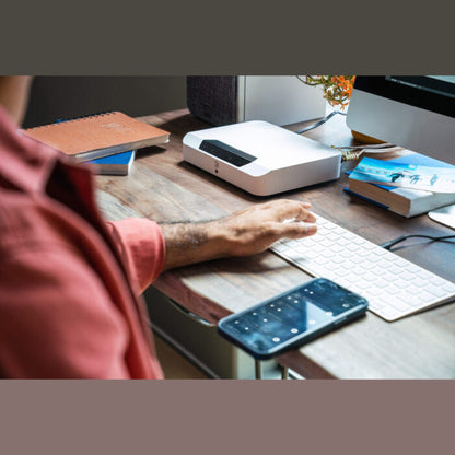 Bluesound Powernode EDGE Streaming-Verstärker Weiss Lifestyle auf Schreibtisch neben Tastatur und Monitor