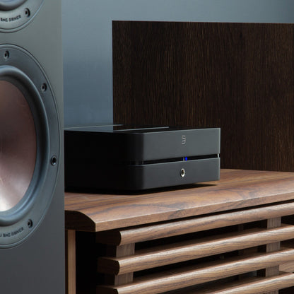 Bluesound Powernode N331 Streaming-Verstärker Schwarz Lifestyle auf Sideboard zwischen Standlautsprechern