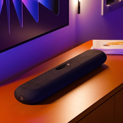 Bluesound Pulse Cinema Mini Soundbar Schwarz Lifestyle unter dem Fernseher bei farbigem Ambientelicht