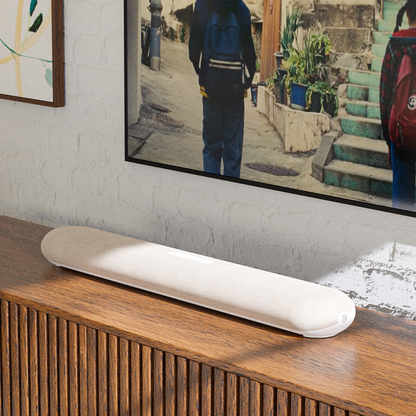 Bluesound Pulse Cinema Mini Soundbar Tan Lifestyle unter dem Fernseher auf dunklem Sideboard
