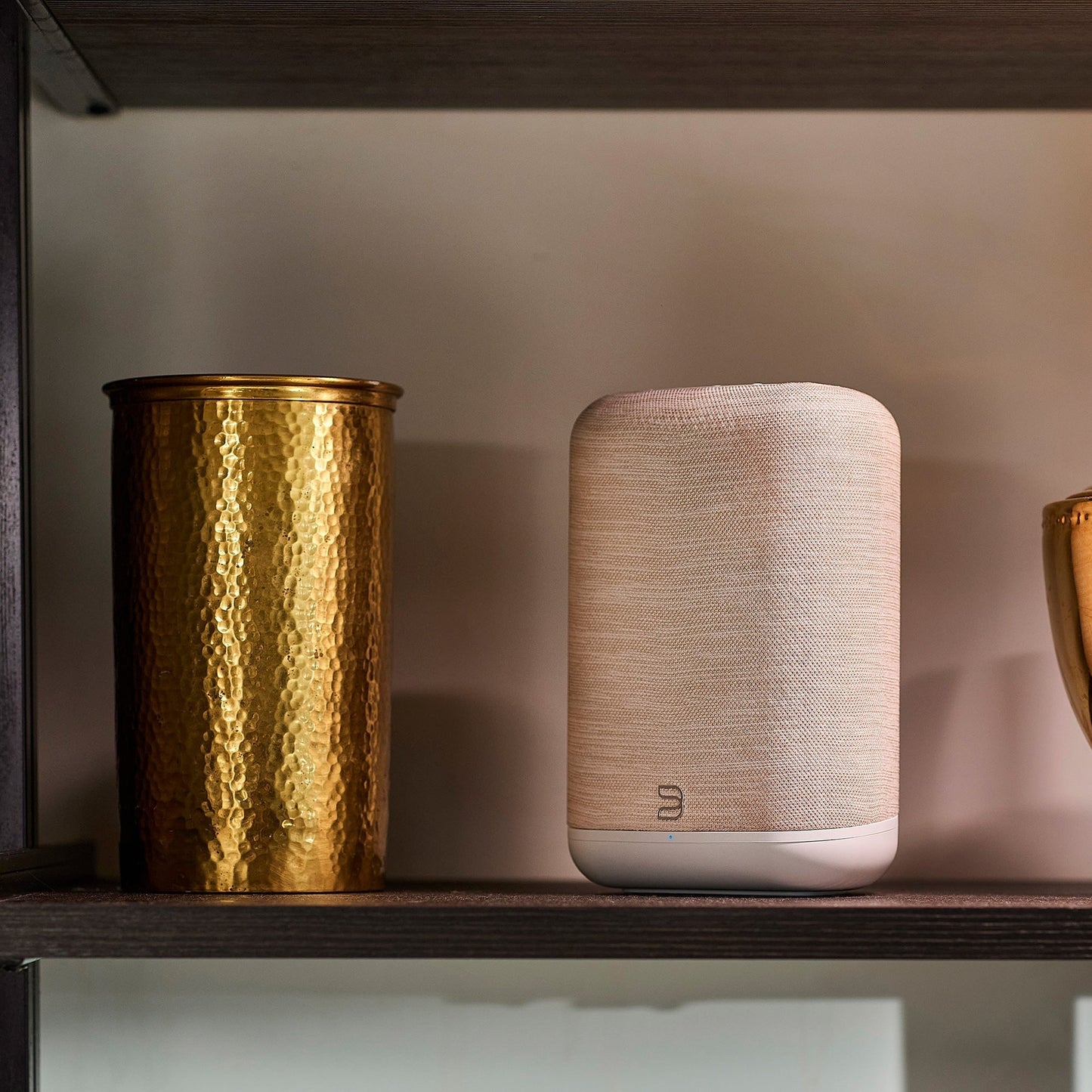 Bluesound Pulse Flex 2025 Streaming-Lautsprecher Beige Lifestyle im Regal neben Messingvase