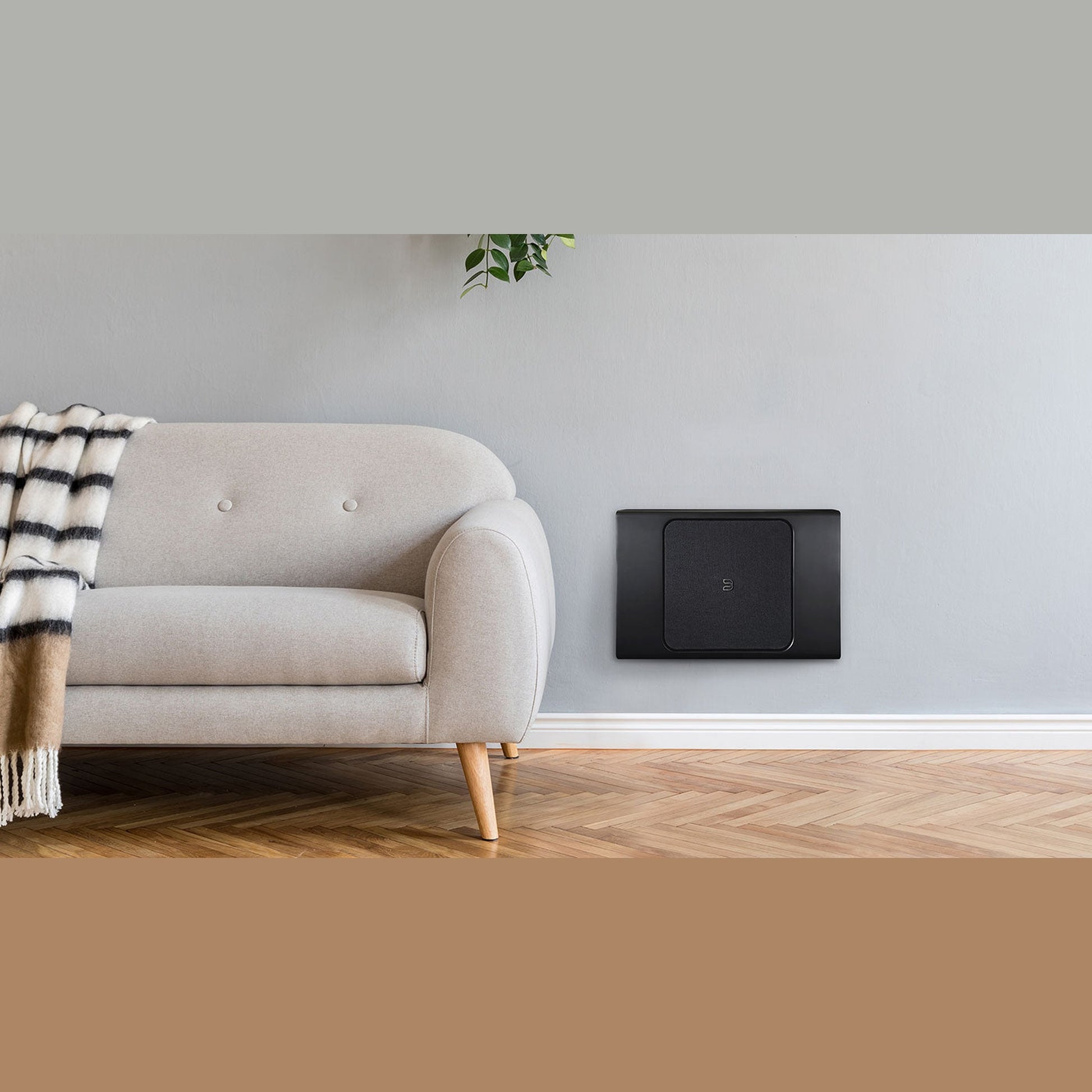 Bluesound Pulse Sub+ Subwoofer Schwarz Lifestyle an der Wand montiert neben Sofa