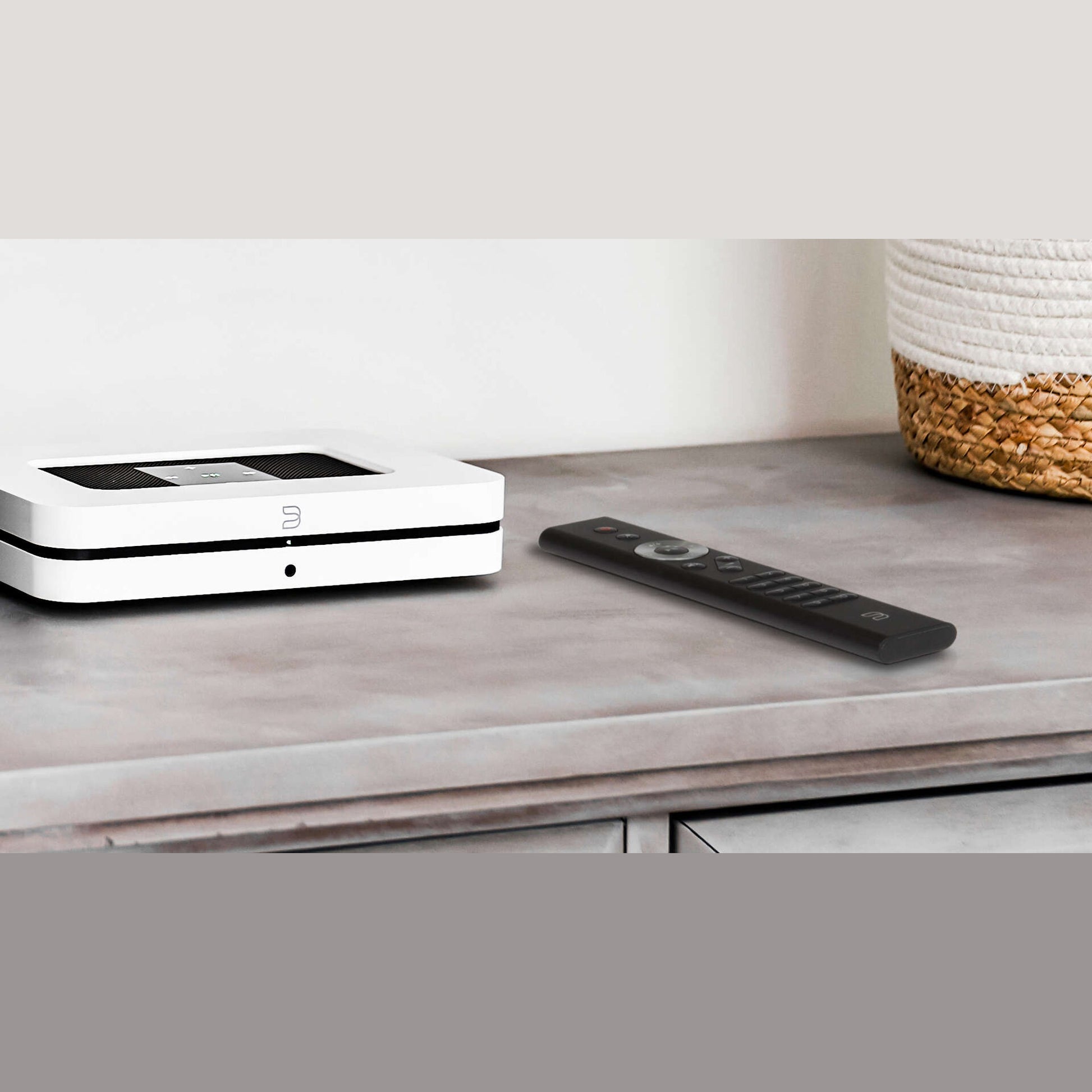Bluesound RC1 Fernbedienung Schwarz Lifestyle auf Steinablage neben Bluesound Node