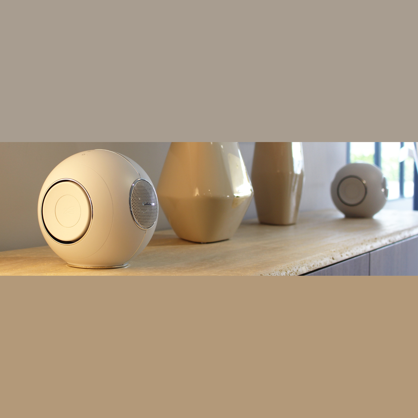 Cabasse The Pearl Myuki Aktivlautsprecher Lifestyle, zwei Geräte auf heller Sideboard-Platte in Weiss