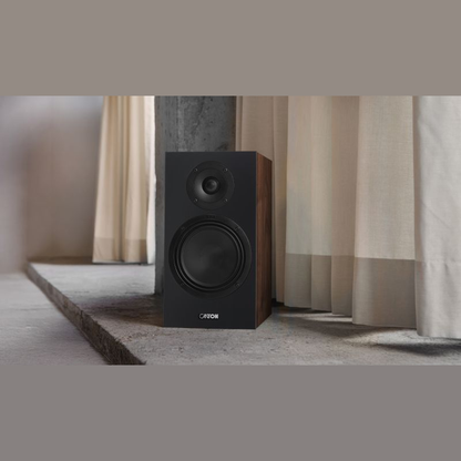 Canton GLE 30 S2 Regallautsprecher Nussbaum Lifestyle auf Betonsockel vor hellem Vorhang