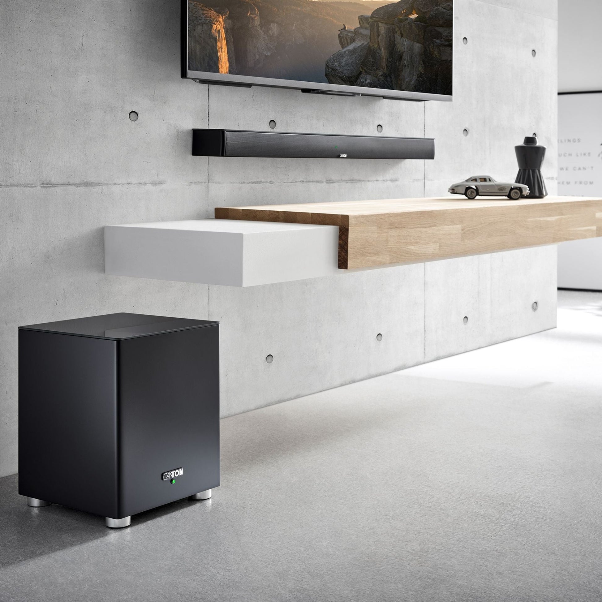 Canton Smart Soundbar 10 S2 Soundbar Schwarz Lifestyle an Betonwand mit Fernseher und Subwoofer