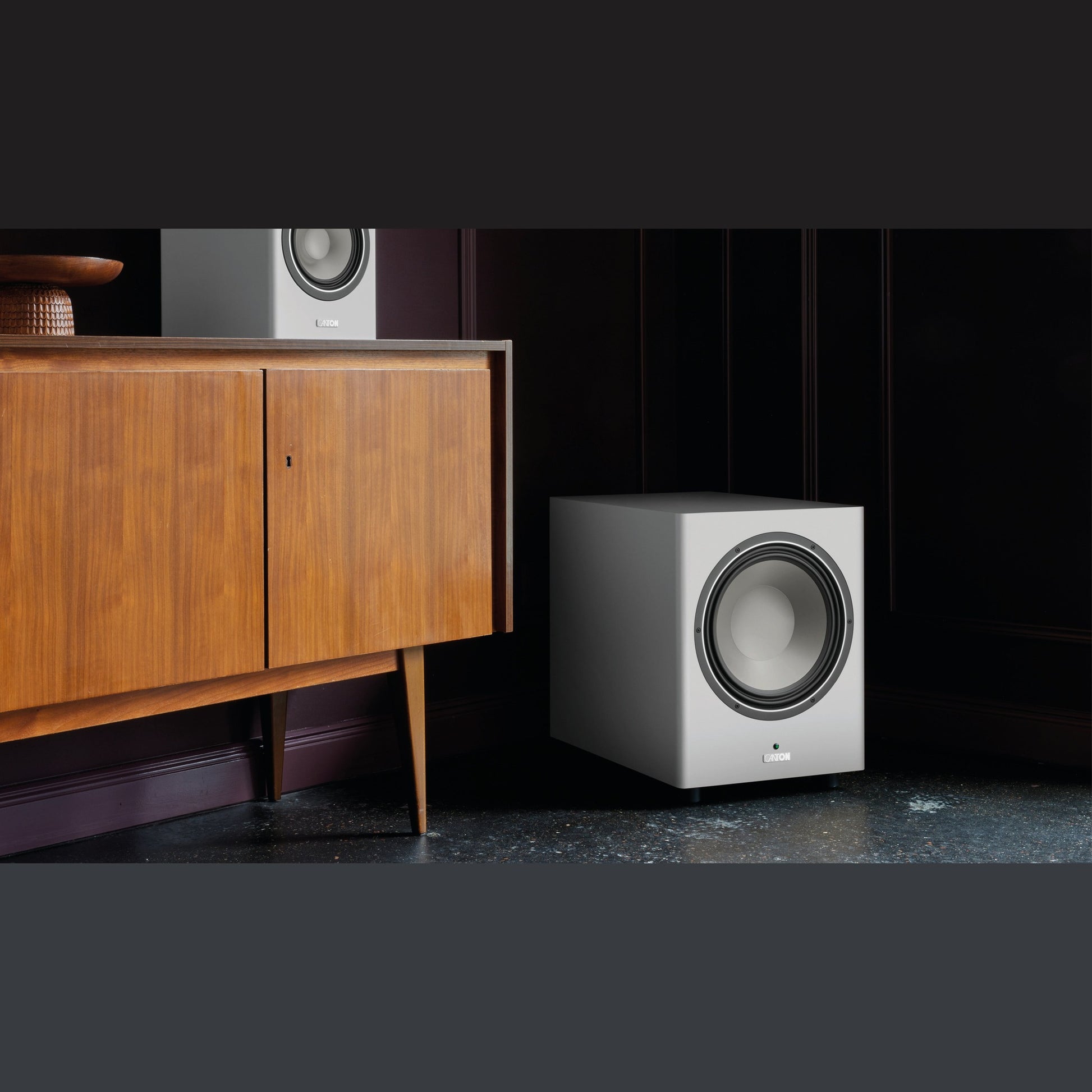 Canton Townus Sub 12 Aktiv-Subwoofer Weiss Lifestyle neben einem Sideboard im Wohnraum