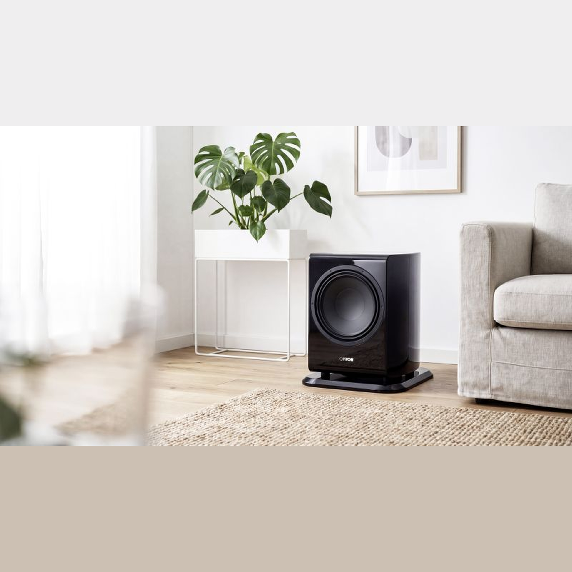 Canton Vento Sub 1 Aktiv-Subwoofer Lifestyle neben Sessel und Beistelltisch im hellen Raum, Schwarz