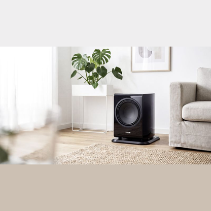 Canton Vento Sub 1 Aktiv-Subwoofer Lifestyle neben Sessel und Beistelltisch im hellen Raum, Schwarz