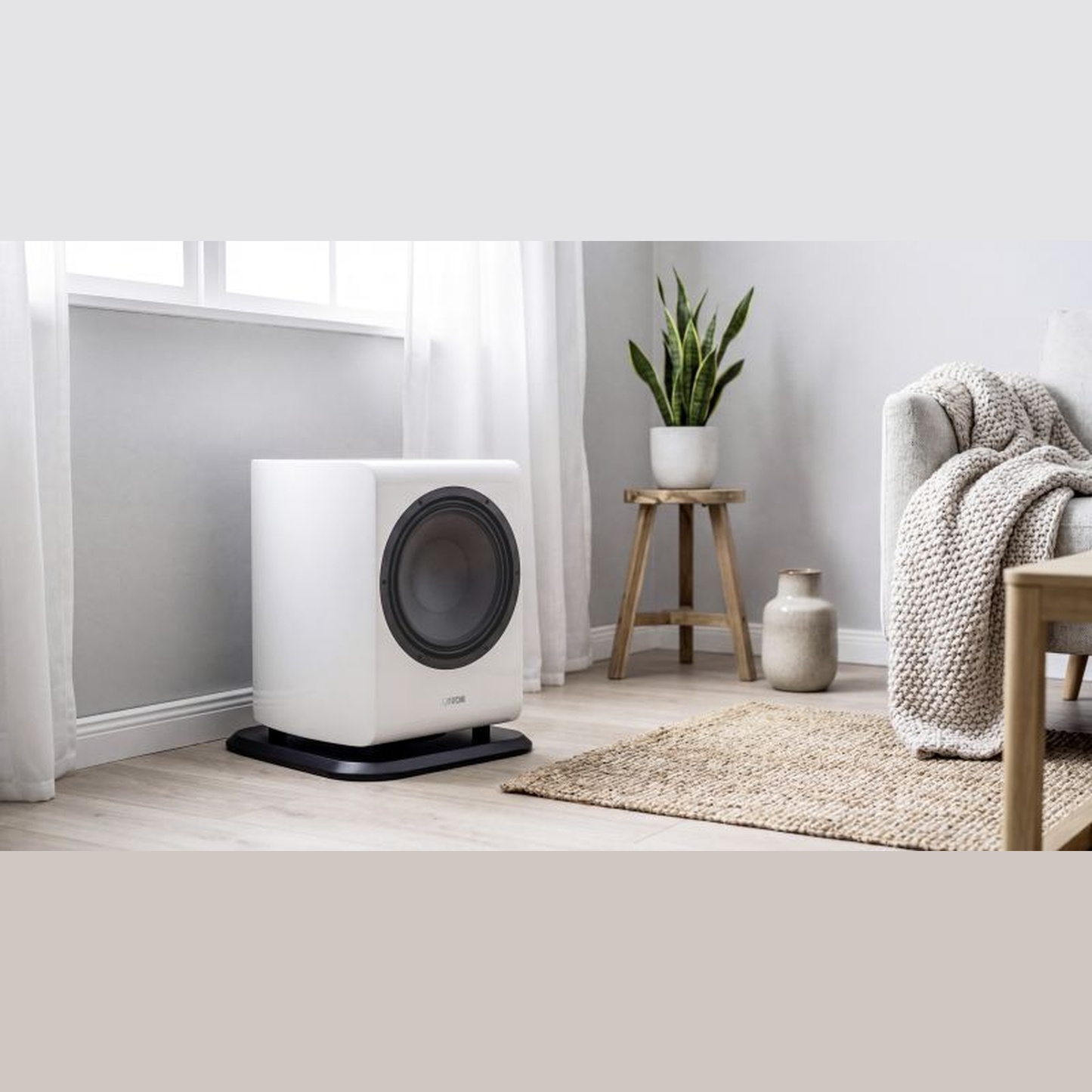 Canton Vento Sub 1 Aktiv-Subwoofer Lifestyle am Fenster neben Hocker und Wolldecke, Weiss matt