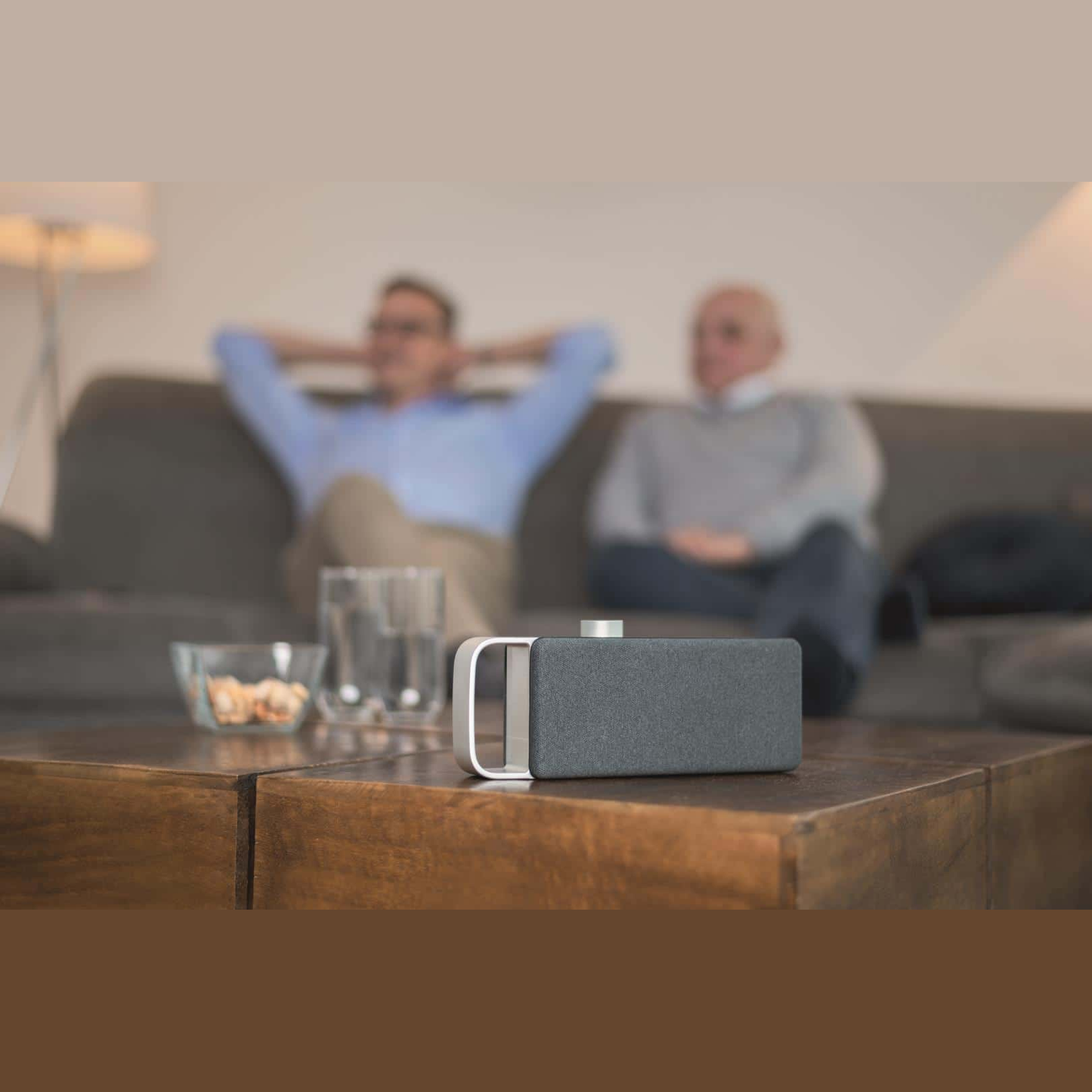 Faller OSKAR TV-Sprachverstärker Lifestyle auf dem Couchtisch im Wohnzimmer vor der Sitzgruppe