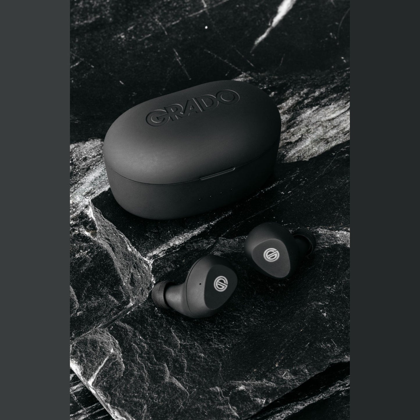 Grado GT220 True-Wireless-In-Ear-Kopfhörer Lifestyle Ohrhörer neben geschlossener Ladebox auf schwarzem Marmor