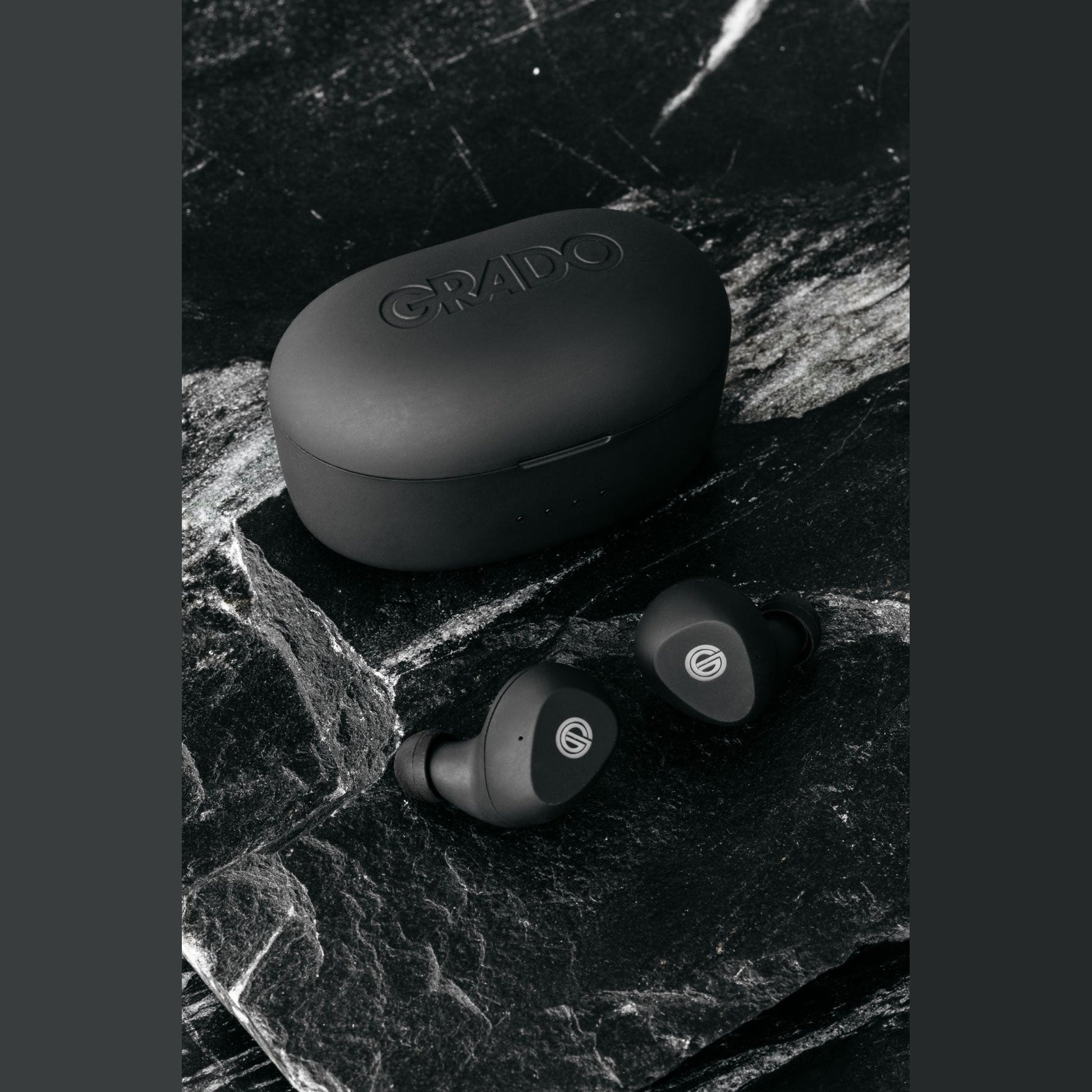 Grado GT220 True-Wireless-In-Ear-Kopfhörer Lifestyle Ohrhörer neben geschlossener Ladebox auf schwarzem Marmor