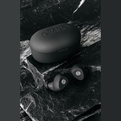 Grado GT220 True-Wireless-In-Ear-Kopfhörer Lifestyle Ohrhörer neben geschlossener Ladebox auf schwarzem Marmor