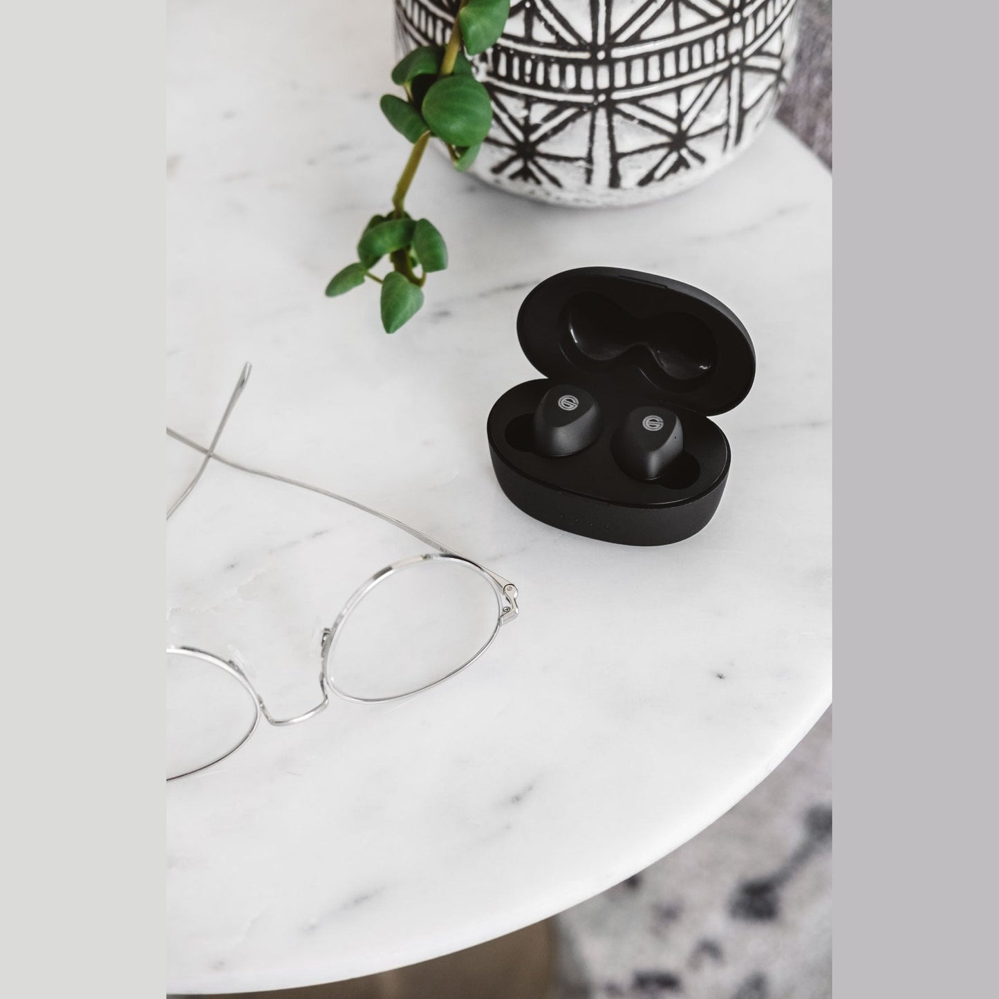 Grado GT220 True-Wireless-In-Ear-Kopfhörer Lifestyle geöffnete Ladebox auf weissem Marmortisch neben Brille