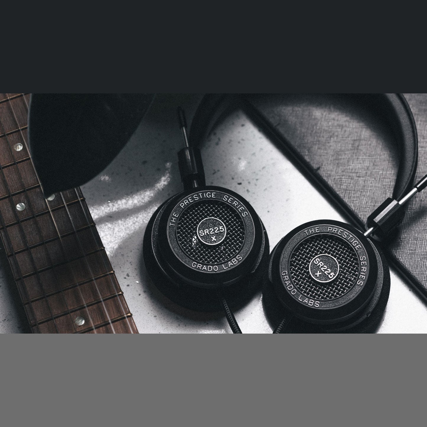 Grado Prestige SR225x Open-Back-Kopfhörer Lifestyle mit beiden Ohrmuscheln neben einer Gitarre