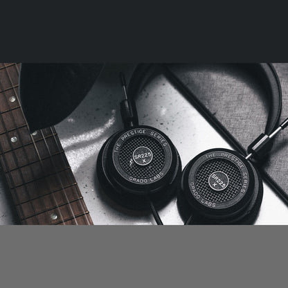 Grado Prestige SR225x Open-Back-Kopfhörer Lifestyle mit beiden Ohrmuscheln neben einer Gitarre