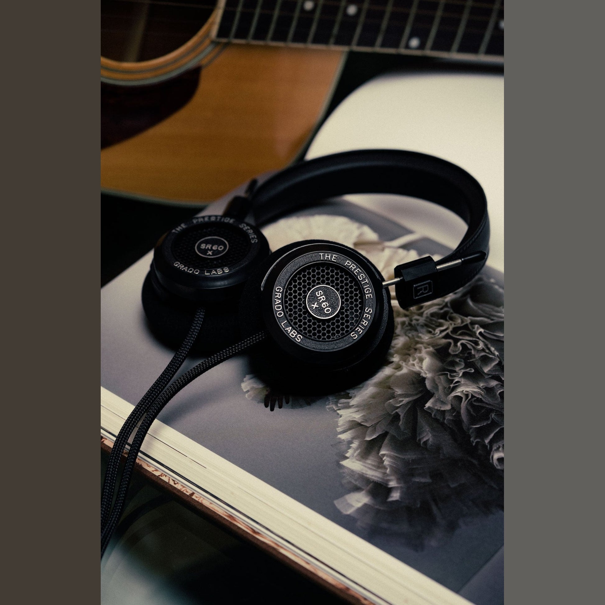 Grado Prestige SR60x Open-Back-Kopfhörer Lifestyle auf einem Bildband vor einer Akustikgitarre