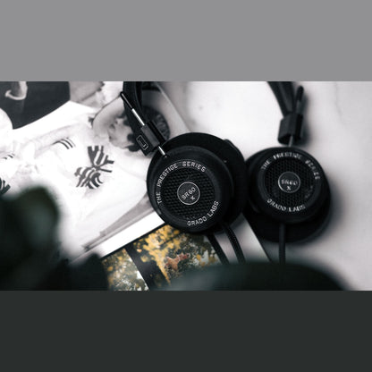Grado Prestige SR60x Open-Back-Kopfhörer Lifestyle mit beiden Ohrmuscheln auf bedruckten Papierbögen