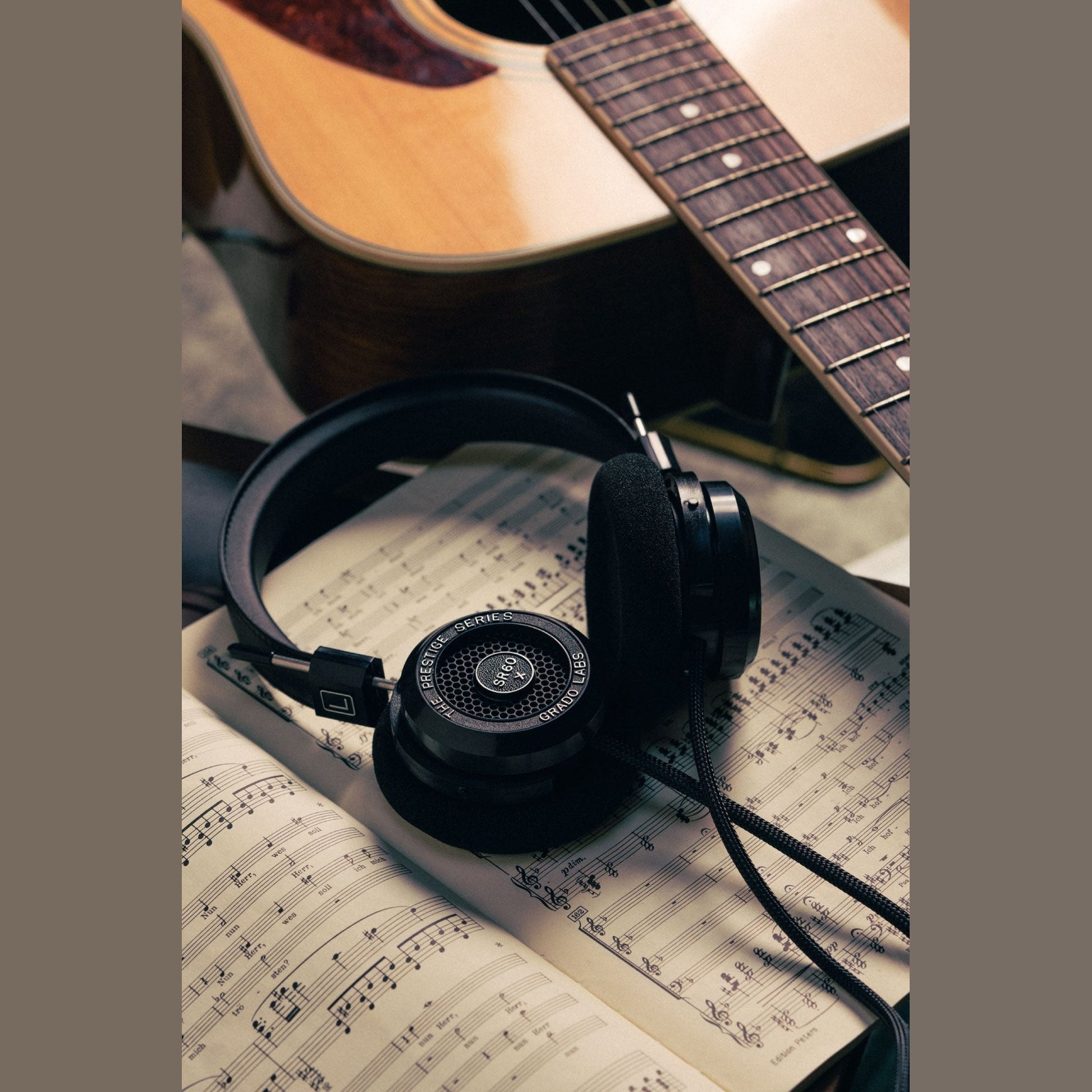 Grado Prestige SR60x Open-Back-Kopfhörer Lifestyle auf Notenblättern neben einer Akustikgitarre