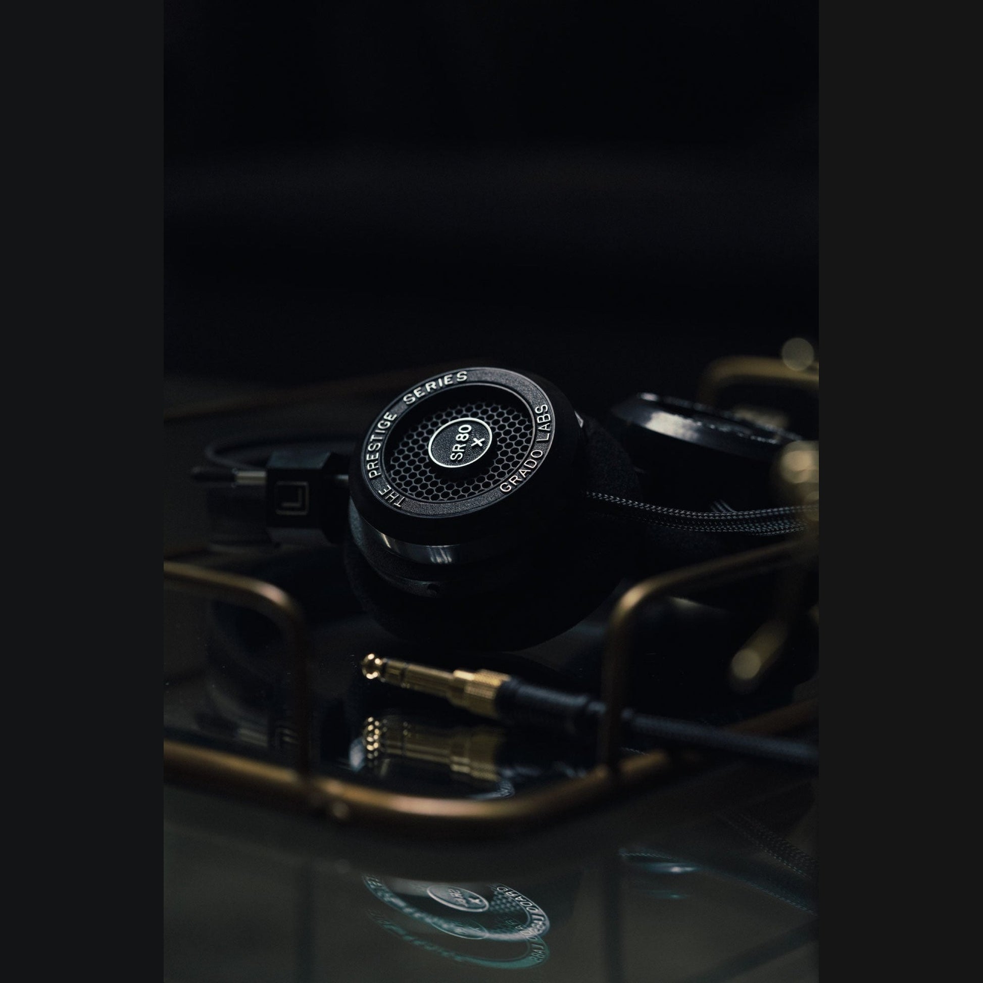 Grado Prestige SR80x Open-Back-Kopfhörer Lifestyle neben goldenen Klinkensteckern auf Glasfläche