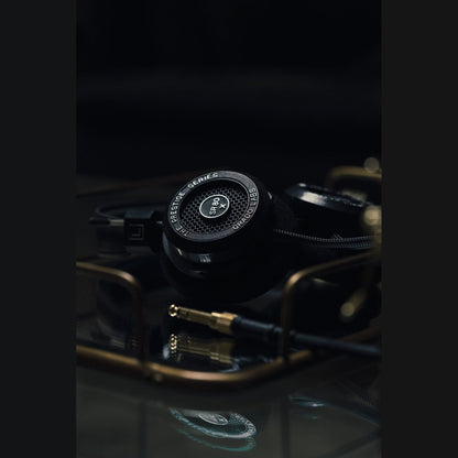 Grado Prestige SR80x Open-Back-Kopfhörer Lifestyle neben goldenen Klinkensteckern auf Glasfläche