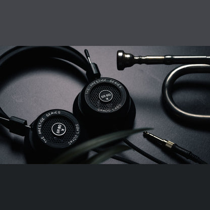 Grado Prestige SR80x Open-Back-Kopfhörer Lifestyle neben Klinkenstecker und Kabel auf dunkler Fläche