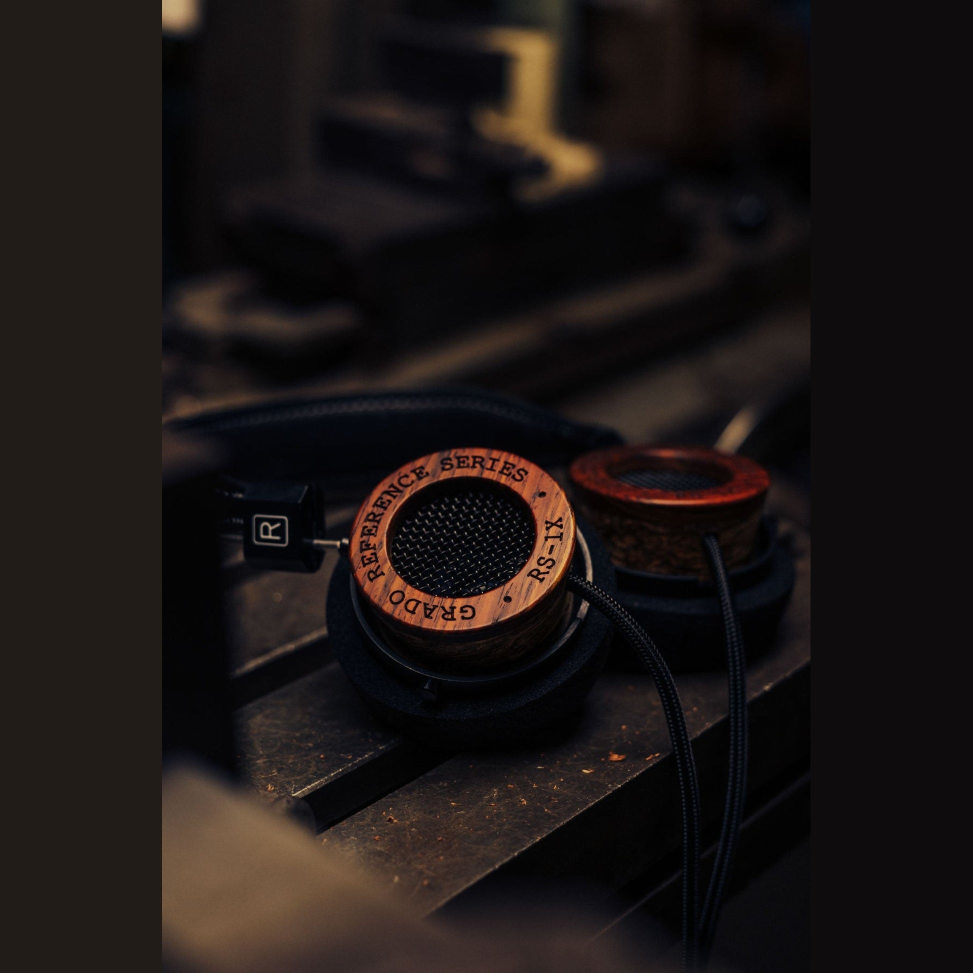 Grado Reference RS1x Open-Back-Kopfhörer Lifestyle auf dunklem Maschinentisch neben rotem Holzring