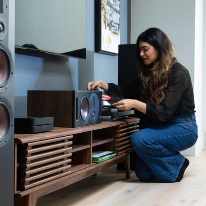 HiFi-Set Bluesound Powernode + Argon Forus 55 Schwarz Lifestyle: Anlage im TV-Möbel, Frau legt eine Schallplatte auf