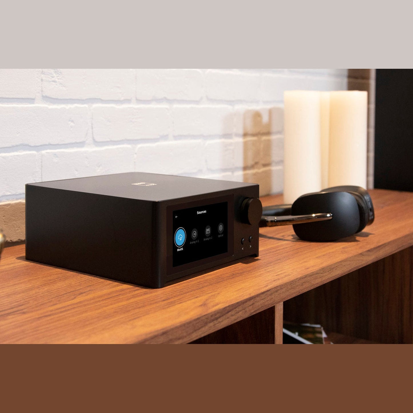 NAD C700 V2 BluOS Streaming-Vollverstärker Lifestyle 6 mit Kopfhörer und Kerzen auf Sideboard