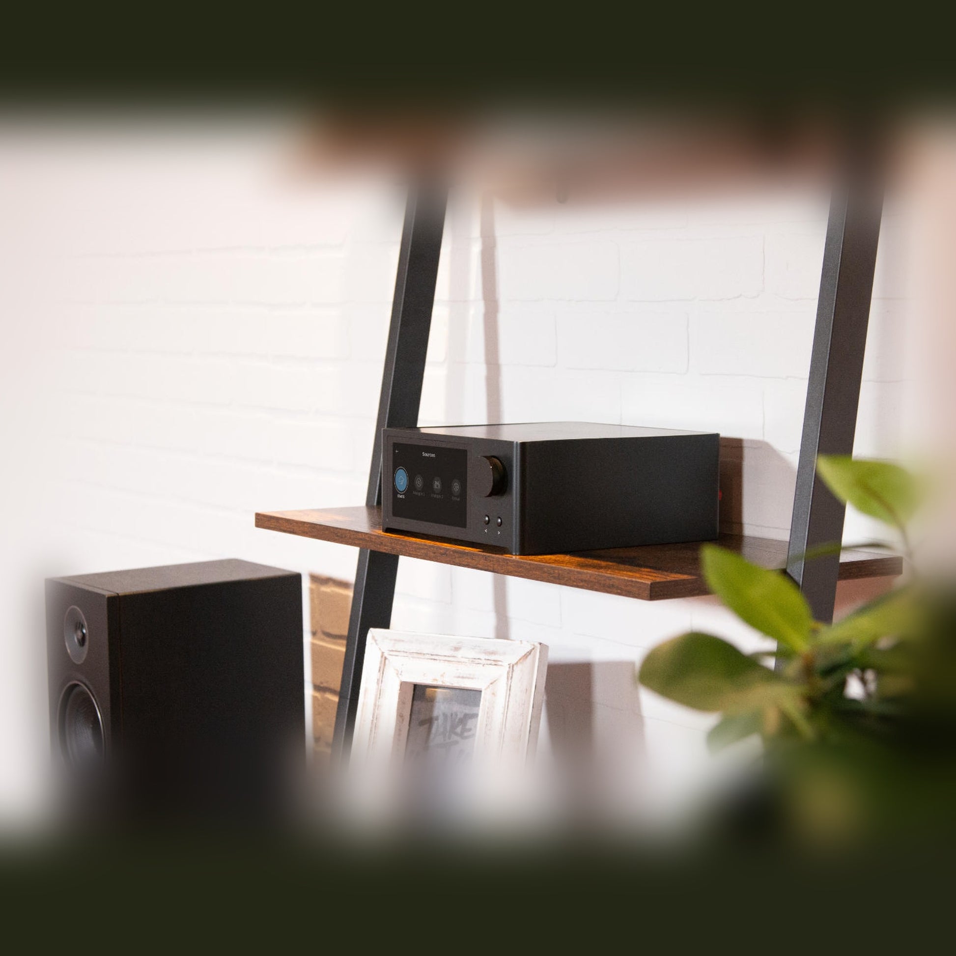NAD C700V2 BluOS Streaming-Vollverstärker Lifestyle auf Wandregal neben PMC-Standlautsprecher