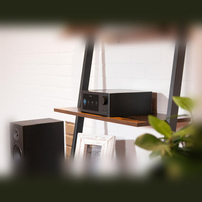 NAD C700V2 BluOS Streaming-Vollverstärker Lifestyle auf Wandregal neben PMC-Standlautsprecher