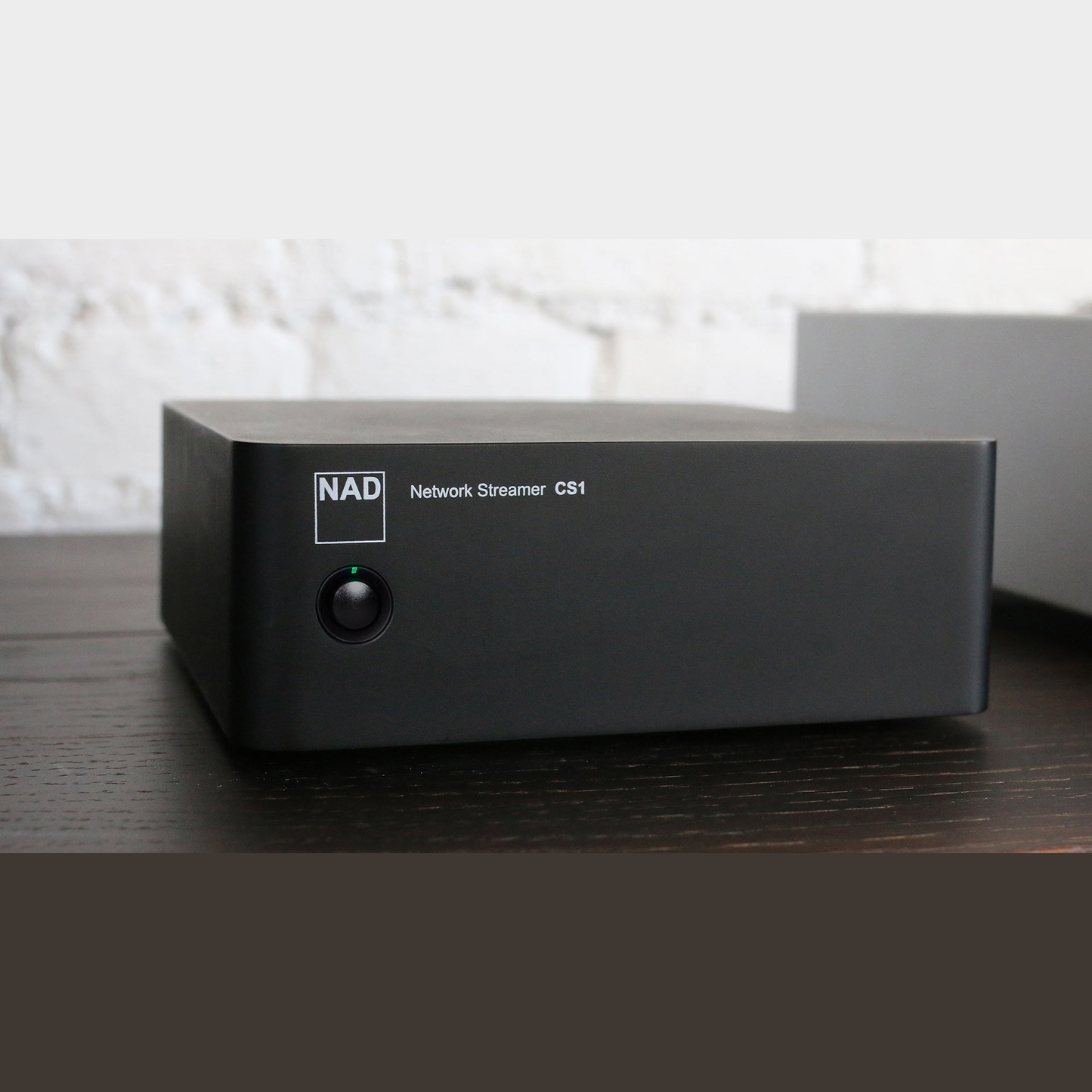 NAD CS1 Netzwerk-Streamer Lifestyle auf dunklem Sideboard vor weisser Wand