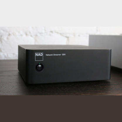 NAD CS1 Netzwerk-Streamer Lifestyle auf dunklem Sideboard vor weisser Wand