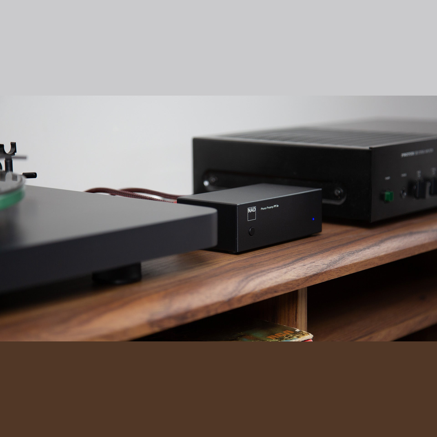 NAD PP 2e Phono-Vorverstärker Lifestyle auf Sideboard mit Plattenspieler und Verstärker