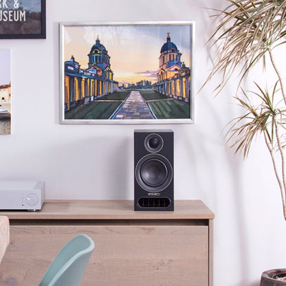 PMC Prodigy1 Regallautsprecher Schwarz Lifestyle auf Sideboard vor Bilderwand