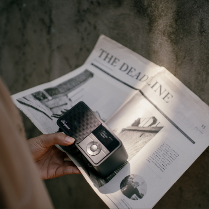 Sangean DDR-7X DAB+ Holzradio mit Akku Lifestyle in der Hand über aufgeschlagener Zeitung in Black