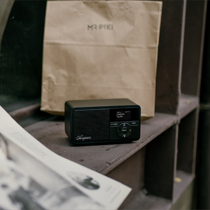 Sangean DDR-7X DAB+ Holzradio mit Akku Lifestyle auf Steinstufe neben Papiertüte in Black