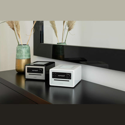 Sonoro Elite Internetradio Lifestyle mit zwei Geräten auf schwarzem Sideboard, Weiss hochglänzend