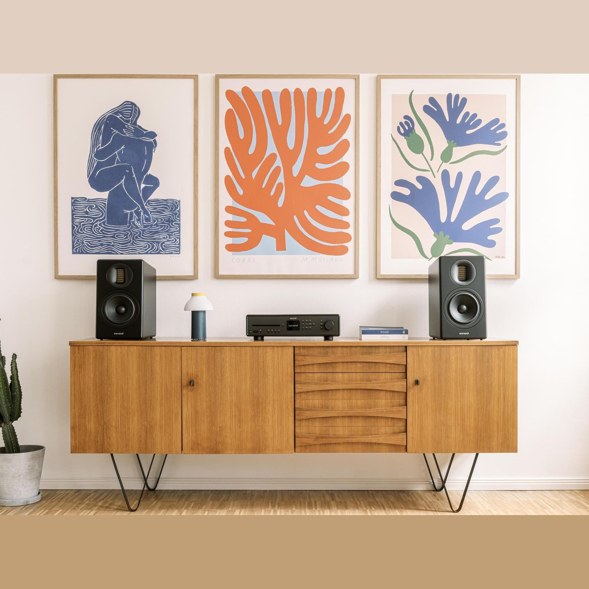 Sonoro Orchestra Gen.2 Regallautsprecher Lifestyle Paar auf Sideboard vor Kunstdrucken, Schwarz matt