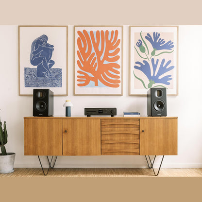 Sonoro Orchestra Gen.2 Regallautsprecher Lifestyle Paar auf Sideboard vor Kunstdrucken, Schwarz matt