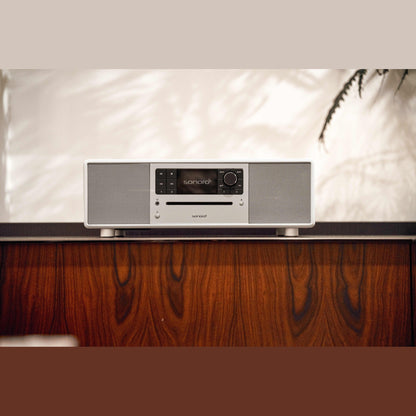 Sonoro Prestige All-in-One Lifestyle auf dunklem Holzsideboard, Weiss hochglänzend