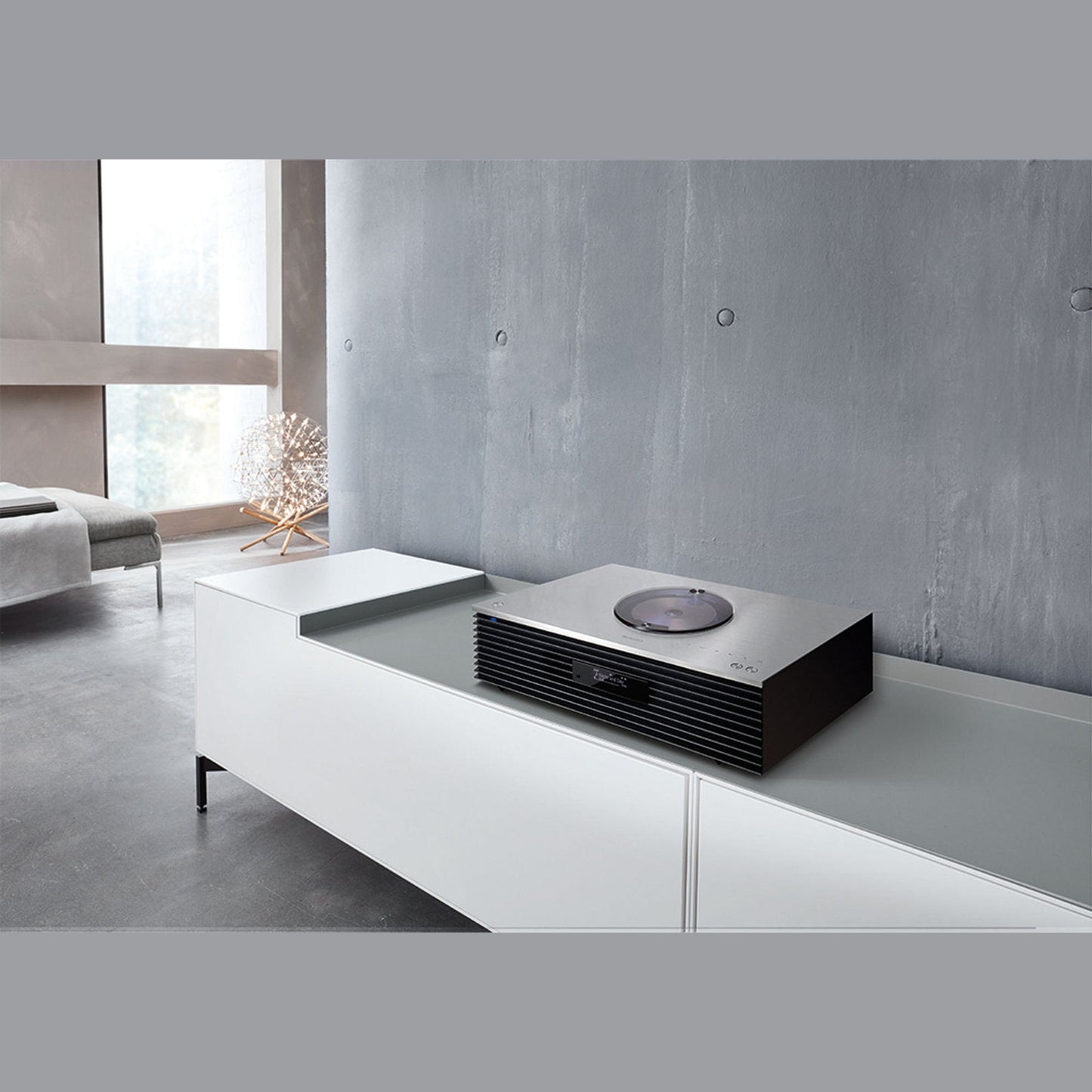 Technics SC-C70MK2 Kompaktanlage Silber Lifestyle auf weissem Sideboard vor Betonwand